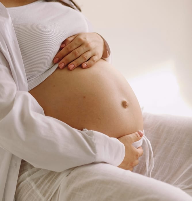 Laser Vaginal Rejuvenation | A close-up photo of a pregnant woman holding her belly.